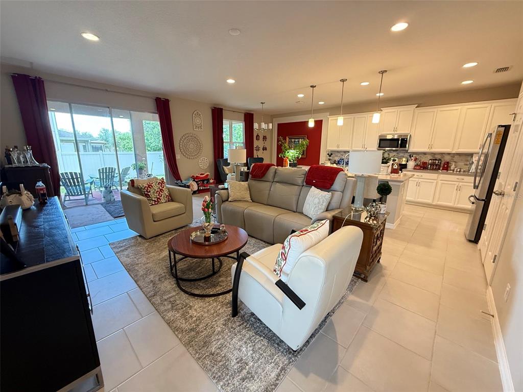 An open-concept living room and kitchen featuring tile floors, neutral furniture, and red accents — 123 GREEN BRANCH BOULEVARD, GROVELAND, FL