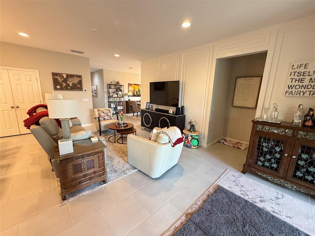 A living room features light tile flooring, a television console, and neutral-toned furniture — 123 GREEN BRANCH BOULEVARD, GROVELAND, FL