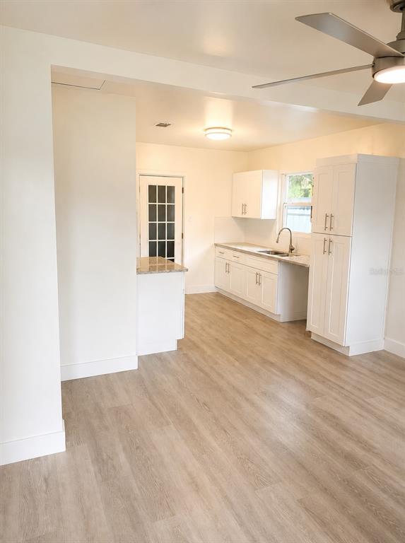 A kitchen with white cabinets, light wood-look flooring, and a ceiling fan — 736 HULL STREET, LAKELAND, FL