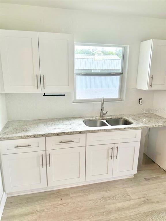 A kitchen features white cabinets, a granite countertop, and a stainless steel double sink — 736 HULL STREET, LAKELAND, FL