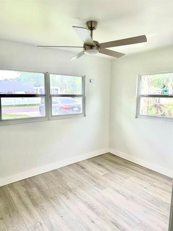 A room with light-colored walls, wood-look flooring, a ceiling fan, and windows overlooking a street — 736 HULL STREET, LAKELAND, FL