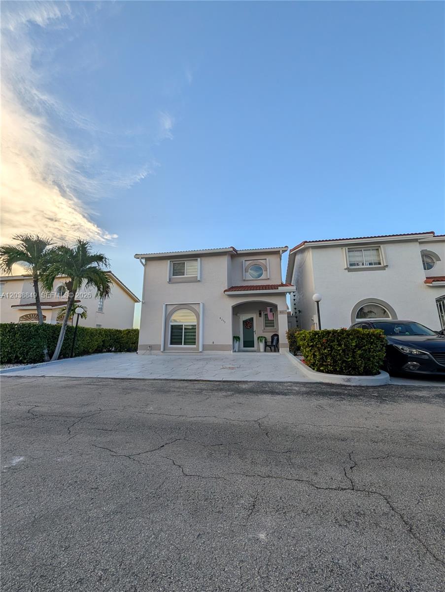 The exterior of a two-story house features a light-colored facade, a tiled roof, and a driveway — 8275 NW 186th St # 801, Hialeah FL 33015, HIALEAH, FL