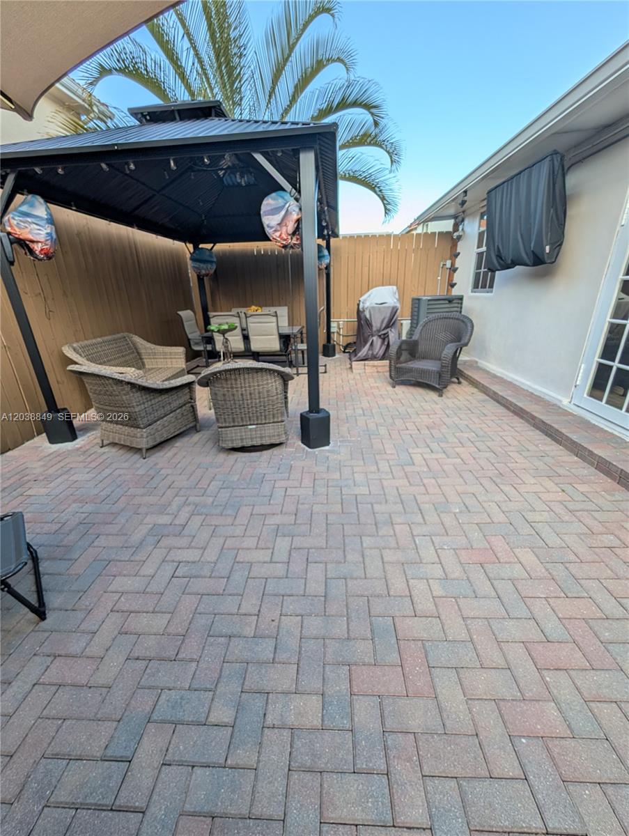 A paved patio features a metal gazebo, wicker furniture, and a fenced backyard area — 8275 NW 186th St # 801, Hialeah FL 33015, HIALEAH, FL