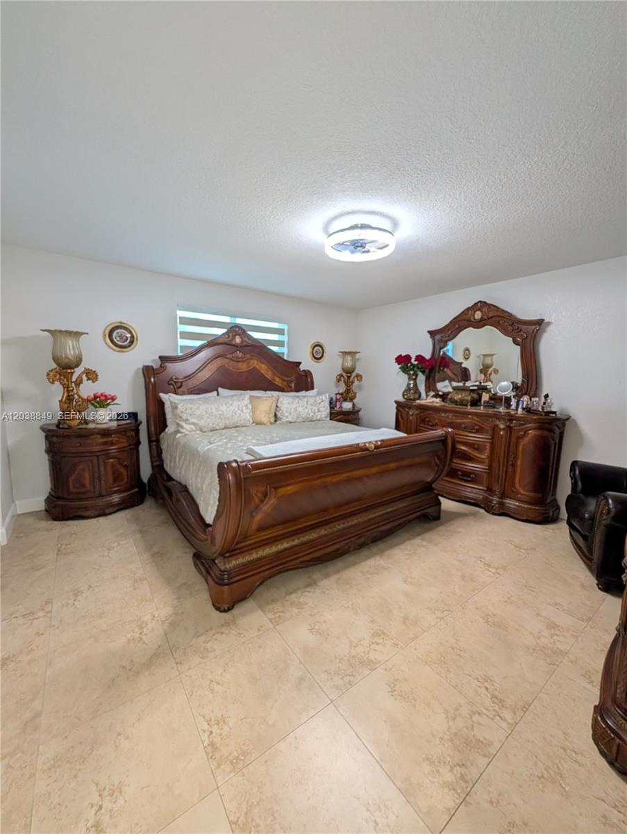 A bedroom features a large wooden bed, an armoire, and a ceiling light fixture — 8275 NW 186th St # 801, Hialeah FL 33015, HIALEAH, FL