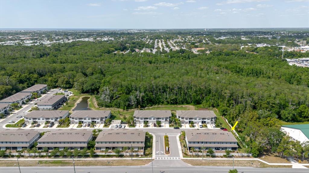 An aerial view shows rows of townhomes with a large wooded area in the background — 5226 FORUM BOULEVARD, HOLIDAY, FL