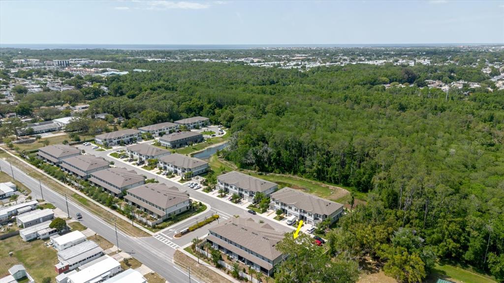 An aerial view shows a residential townhouse complex surrounded by dense forest and nearby roads — 5226 FORUM BOULEVARD, HOLIDAY, FL