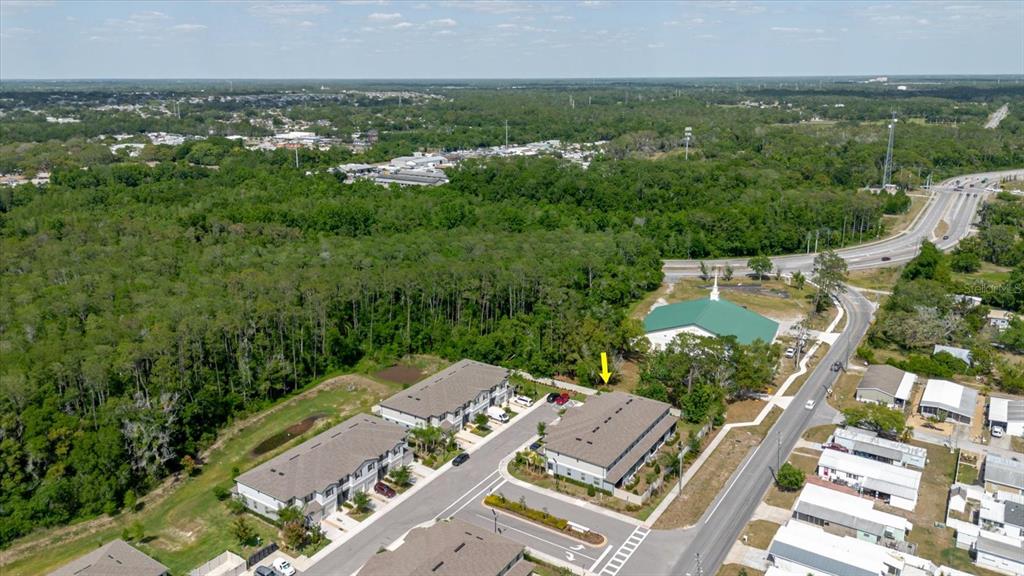 An aerial view shows two multi-story townhome buildings situated next to a wooded area — 5226 FORUM BOULEVARD, HOLIDAY, FL