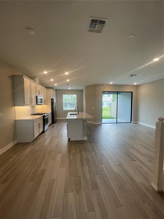 An open-concept kitchen features white cabinetry, a center island, and light wood-look tile flooring — 4596 ALMADA LANE, WESLEY CHAPEL, FL