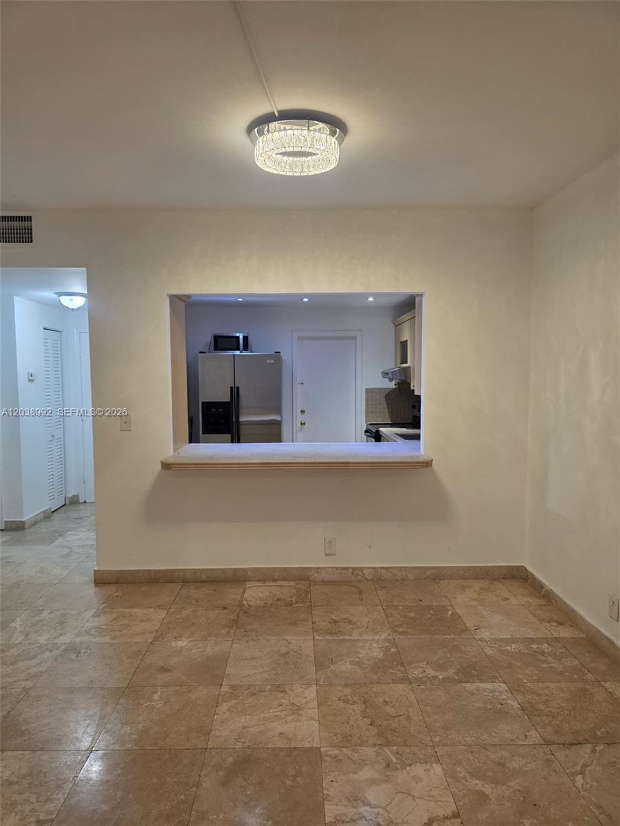 A dining area with tile floors features a pass-through window looking into the kitchen — 1817 S Ocean Dr # 18, Hallandale Beach FL 33009, HALLANDALE BEACH, FL