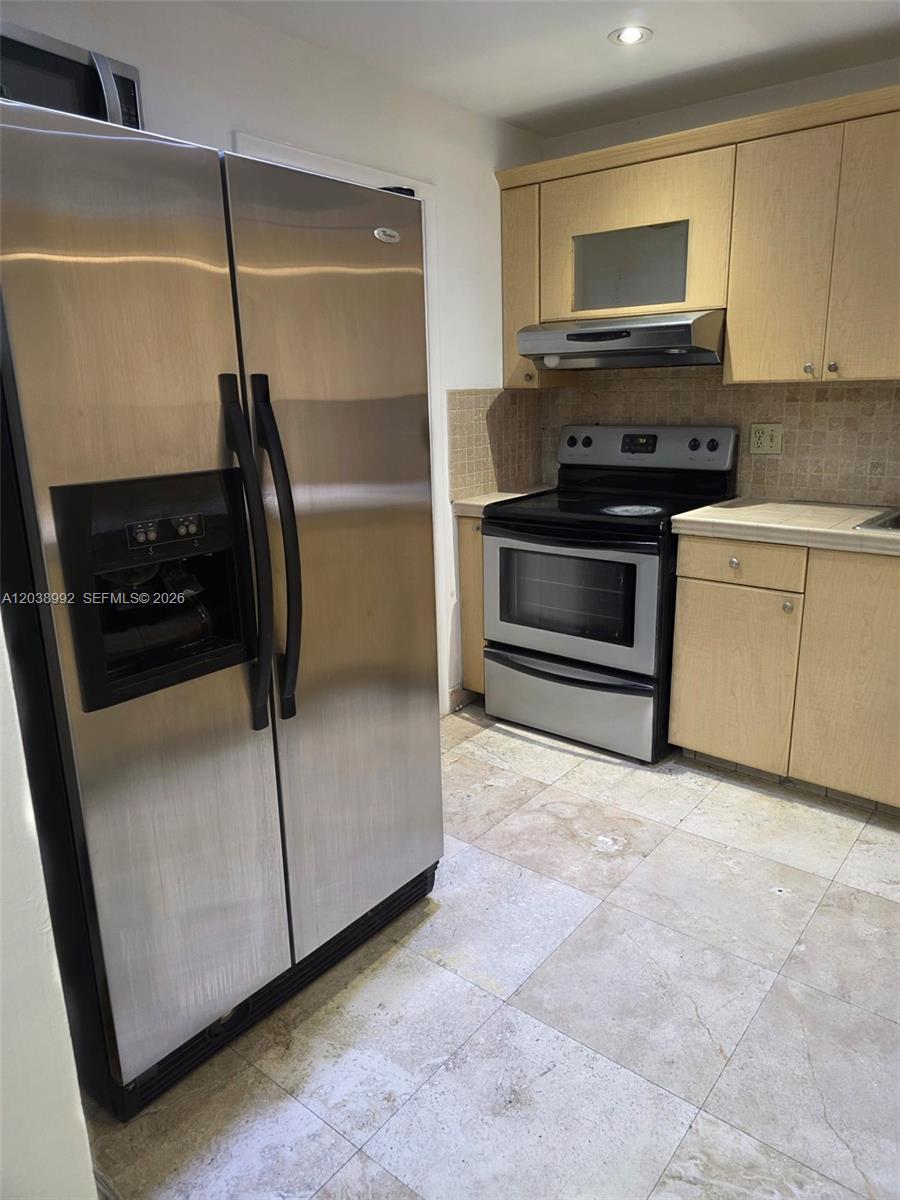 A kitchen features stainless steel appliances, light wood cabinets, and light-colored stone floor tiles — 1817 S Ocean Dr # 18, Hallandale Beach FL 33009, HALLANDALE BEACH, FL