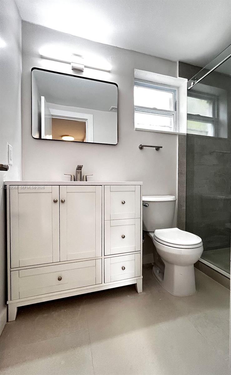 A bathroom features a white vanity, a rectangular mirror, a toilet, and a glass shower — 1301 N 12th Ct # 10A, Hollywood FL 33019, HOLLYWOOD, FL