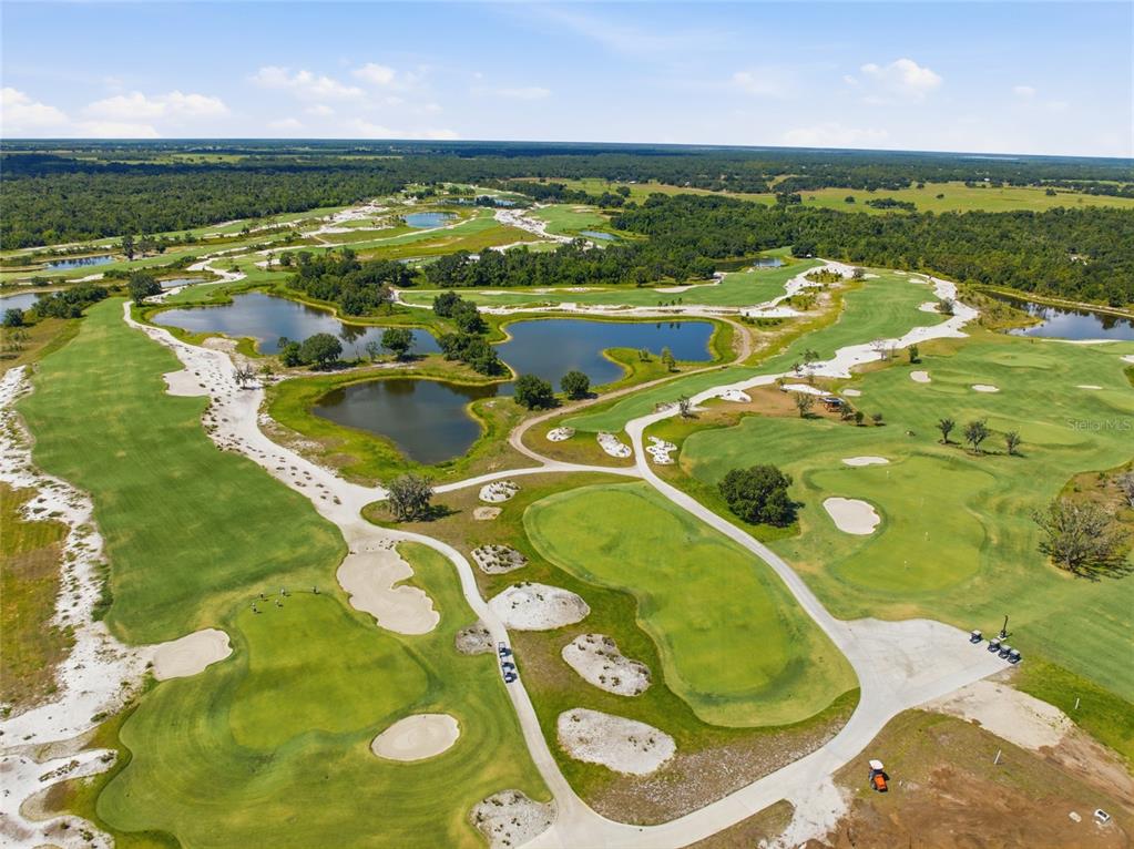 An aerial view of a golf course featuring multiple ponds, sand traps, and paved paths — 34452 SINGLETARY RD, MYAKKA CITY, FL