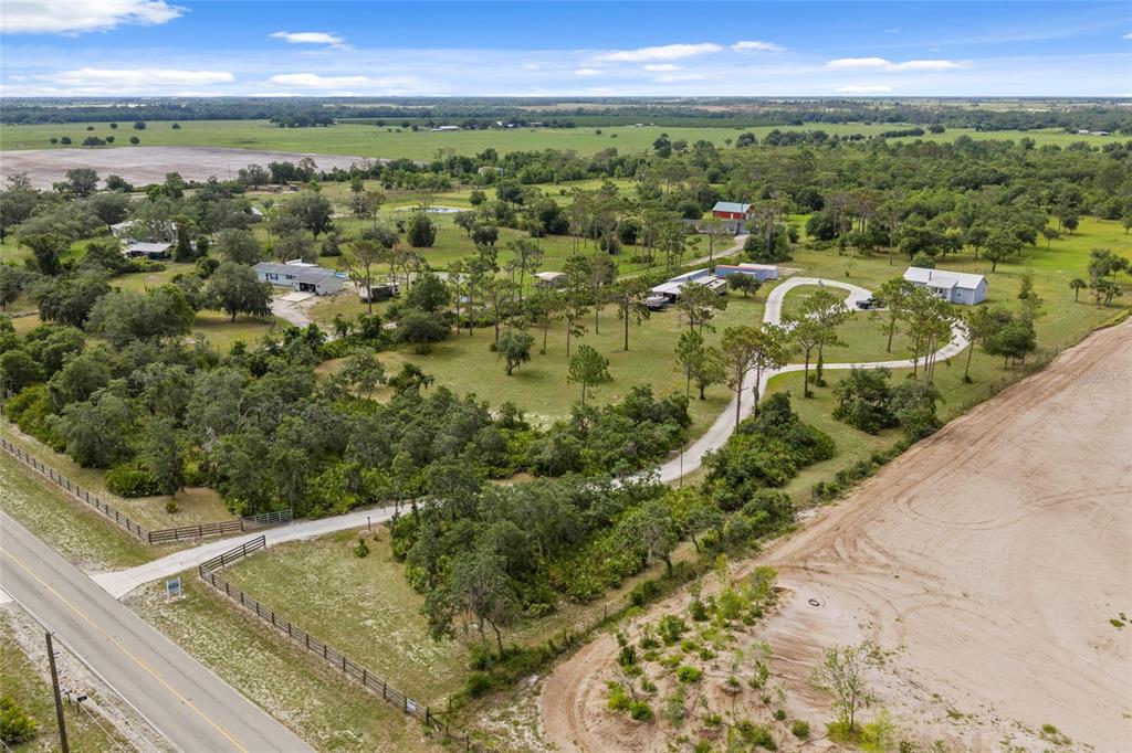 An aerial view shows a rural property with multiple buildings, trees, and a paved driveway — 34452 SINGLETARY RD, MYAKKA CITY, FL
