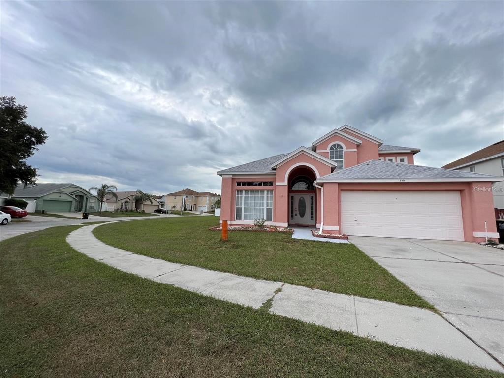 A two-story pink house with a white garage and a curved sidewalk in front — 755 RIGGS CIRCLE, DAVENPORT, FL