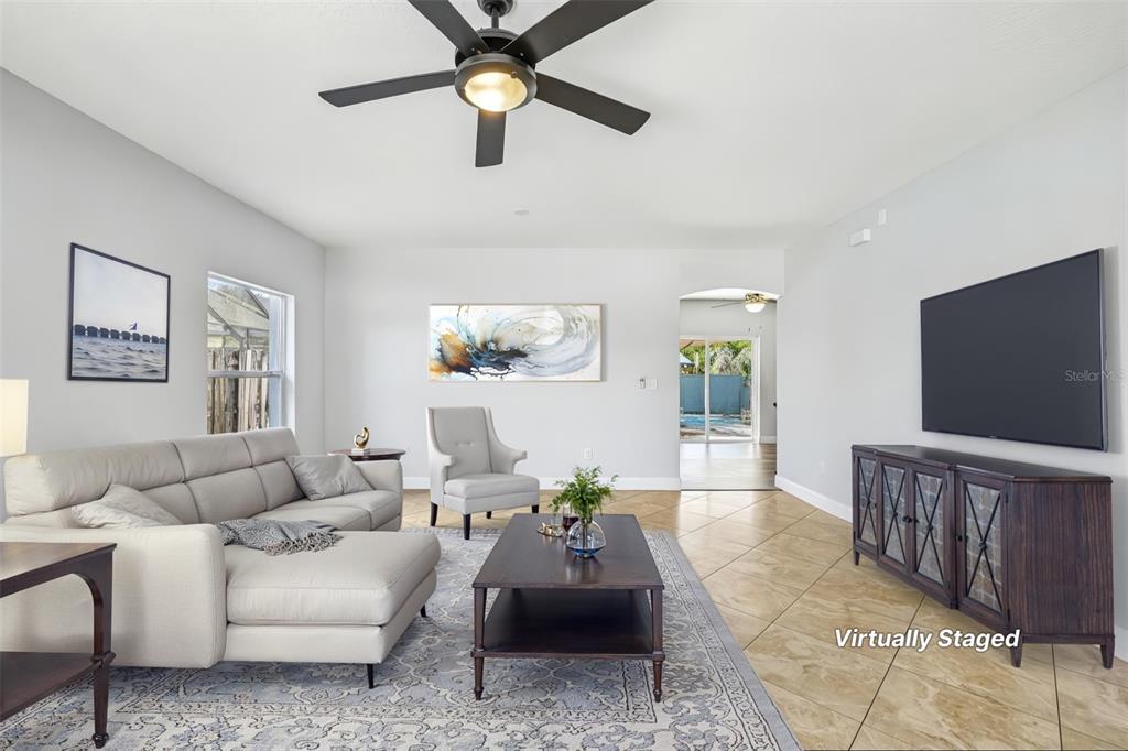 A living room features a sectional sofa, coffee table, armchair, and a wall-mounted television — 24348 SUMMER WIND COURT, LUTZ, FL