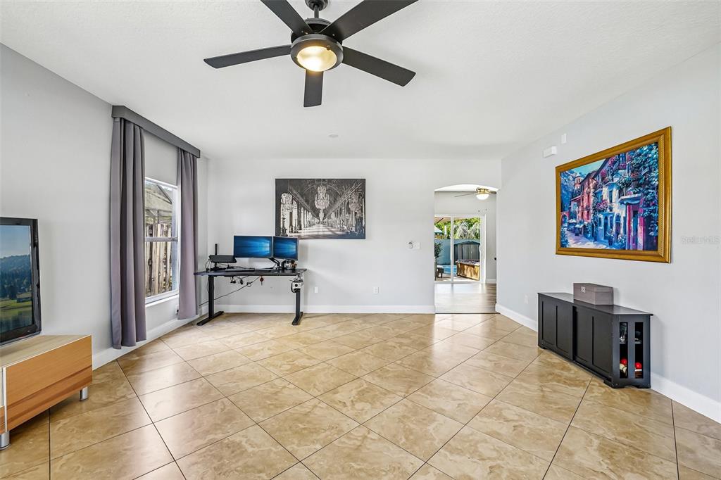 A living room features tile flooring, a ceiling fan, a desk, and a wall painting — 24348 SUMMER WIND COURT, LUTZ, FL