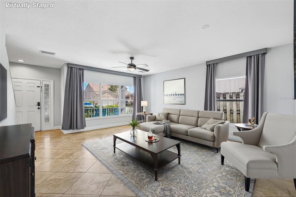 A living room with tile floors, a gray sectional sofa, and large windows with curtains — 24348 SUMMER WIND COURT, LUTZ, FL