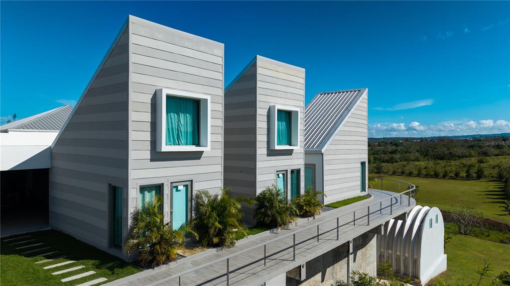 Exterior view of modern, multi-level home with slanted roofs, gray siding, and a metal balcony — 0 "CARRETERA 308 BARRIO MIRADERO", CABO ROJO, PR
