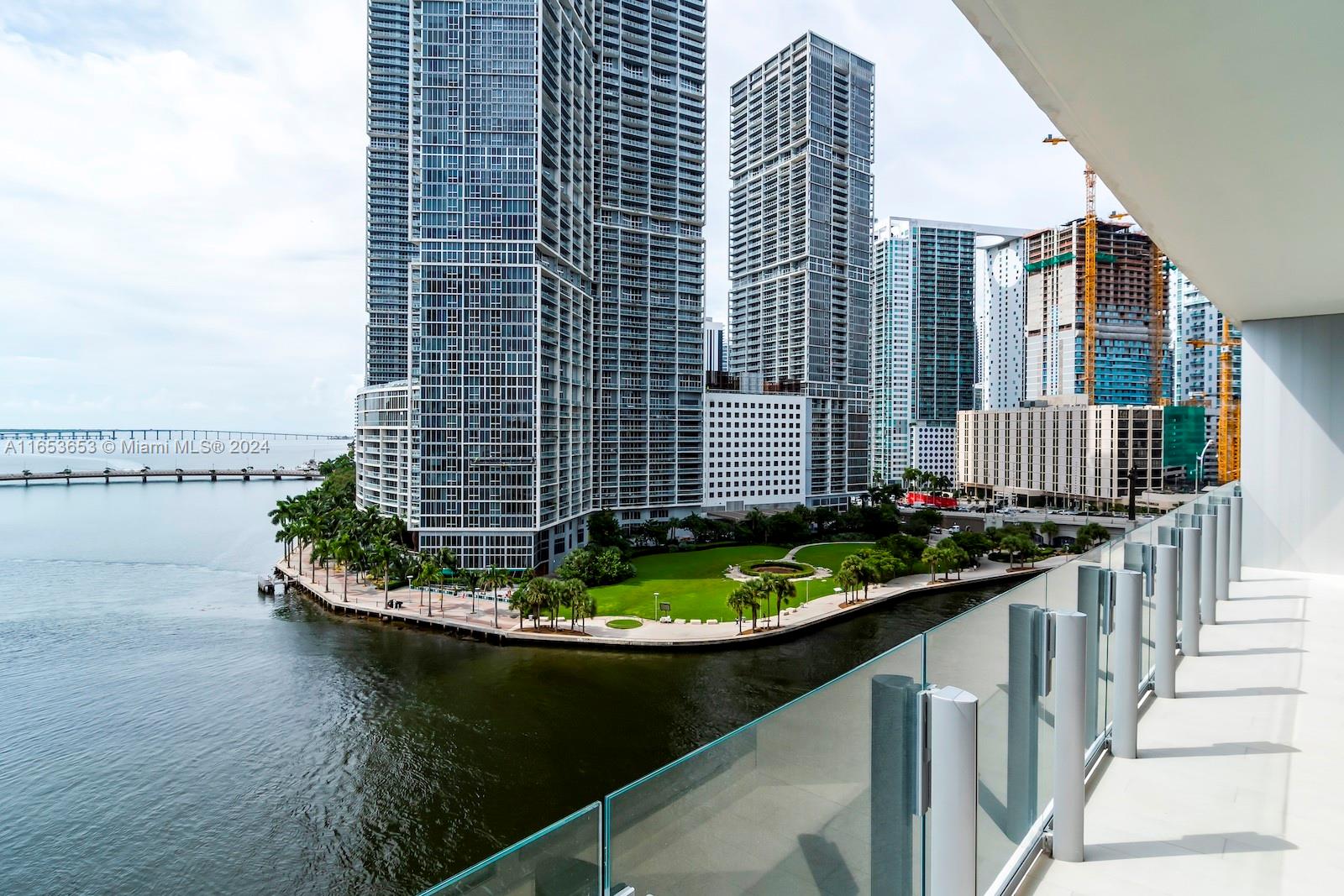 A balcony with a glass railing overlooks a waterfront park and high-rise buildings — 300 Biscayne Blvd Way # 902, Miami FL 33131, MIAMI, FL