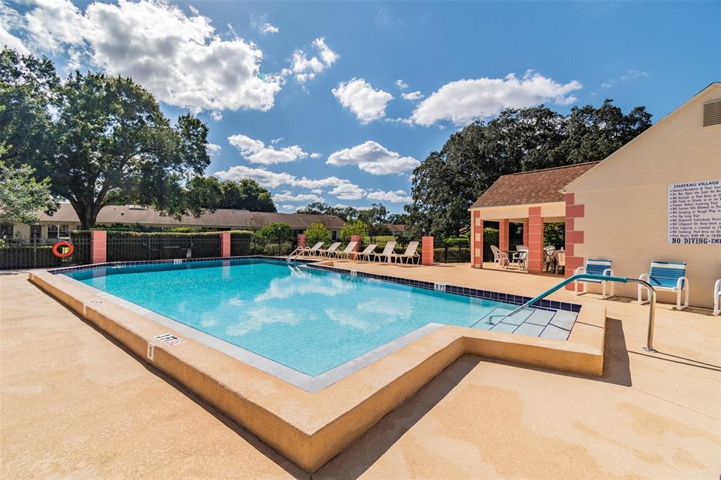 An outdoor swimming pool with a surrounding deck and a small covered pavilion — 11110 CARRIAGE HILL DRIVE UNIT 5, PORT RICHEY, FL