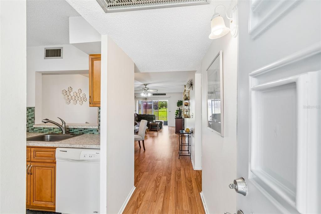 An entryway leads into a kitchen with wood cabinets and a living area beyond — 11110 CARRIAGE HILL DRIVE UNIT 5, PORT RICHEY, FL