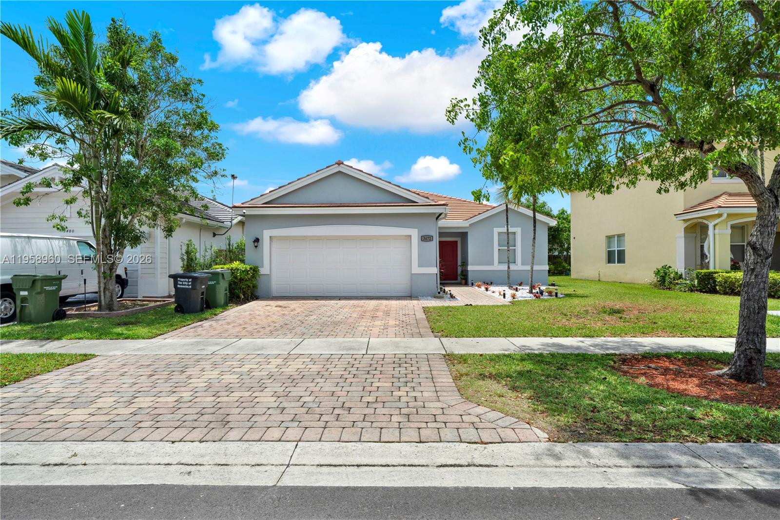 A single-story house with a paved driveway, two-car garage, and a red front door — 3472 NE 2nd St, Homestead FL 33033, HOMESTEAD, FL