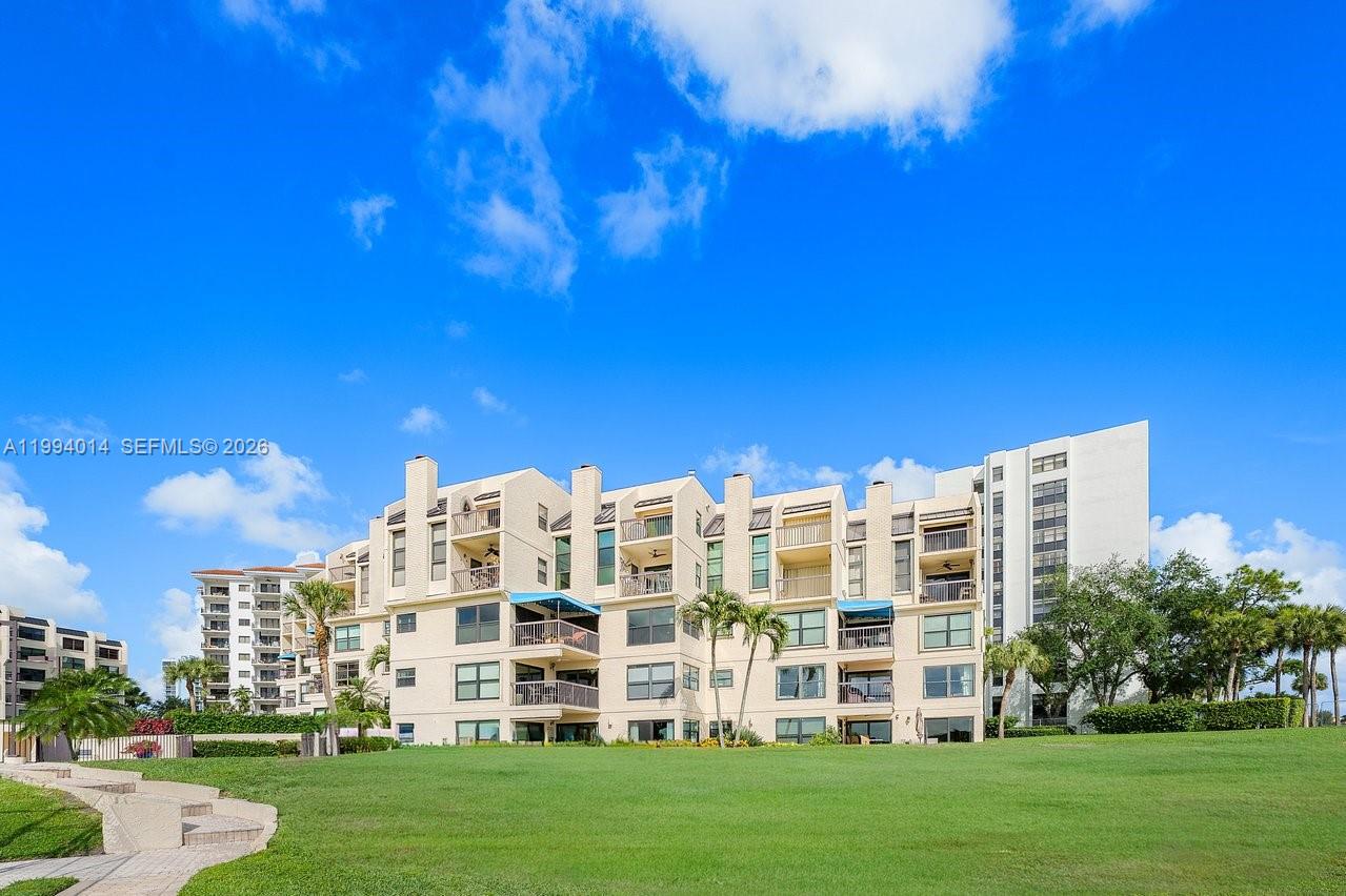 A multi-story residential building with balconies overlooks a large green lawn under a blue sky — 364 Golfview Rd # 505, North Palm Beach FL 33408, NORTH PALM BEACH, FL