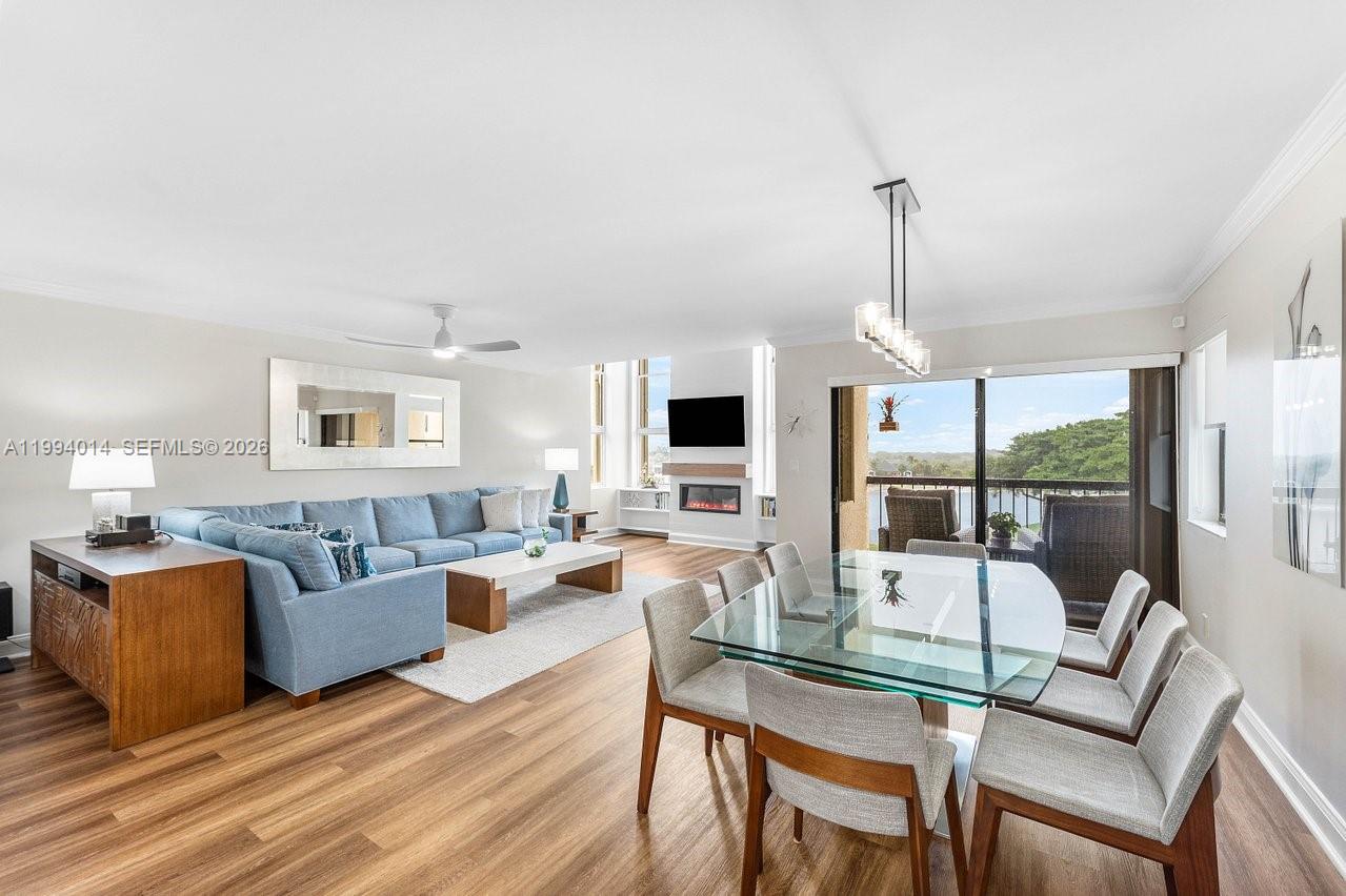 A living and dining area features a blue sectional sofa, glass table, and balcony view — 364 Golfview Rd # 505, North Palm Beach FL 33408, NORTH PALM BEACH, FL