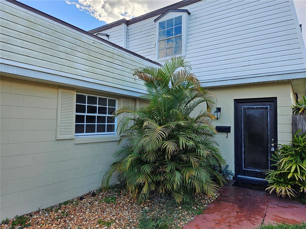 A two-story building exterior features a palm tree, a front door, and a small window — 6640 POT O GOLD LANE, ORLANDO, FL