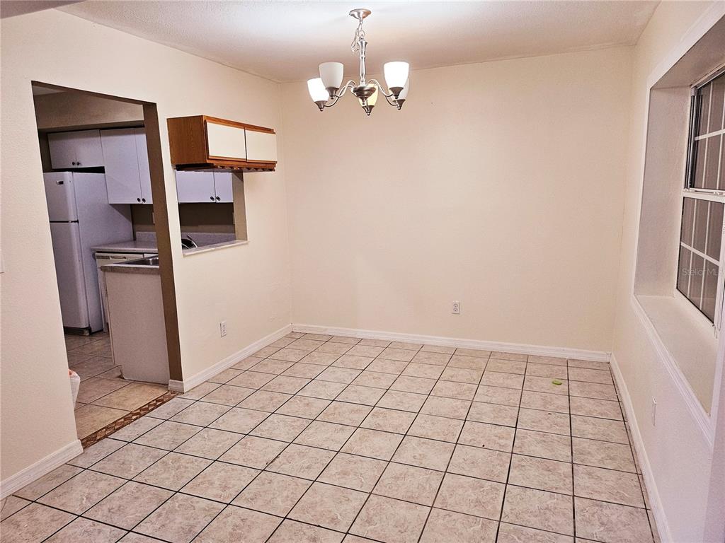 A dining area with tile flooring, a chandelier, and a pass-through window to the kitchen — 6640 POT O GOLD LANE, ORLANDO, FL