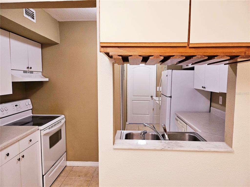 A kitchen features white cabinets, a white stove, a double sink, and a pass-through window — 6640 POT O GOLD LANE, ORLANDO, FL