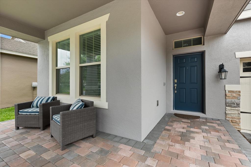 A covered front porch features gray stucco walls, a blue door, and two wicker chairs — 16124 AZURE KEY STREET, WINTER GARDEN, FL