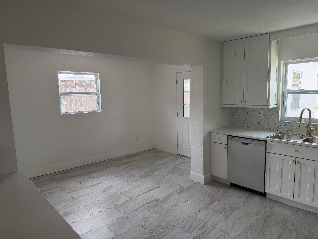 A kitchen with white cabinets, stainless steel appliances, and gray wood-look tile flooring — 632 89TH AVENUE N, ST PETERSBURG, FL