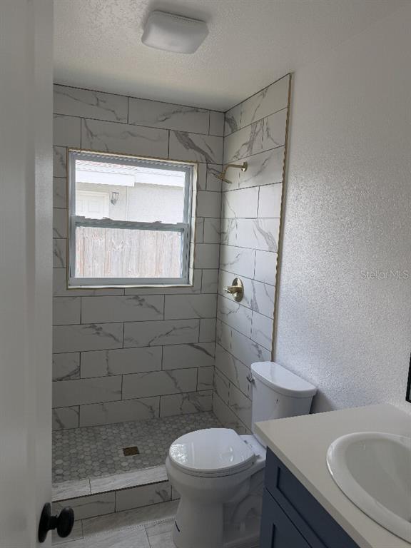A bathroom features a walk-in shower with marble-look tile, a toilet, and a vanity — 632 89TH AVENUE N, ST PETERSBURG, FL