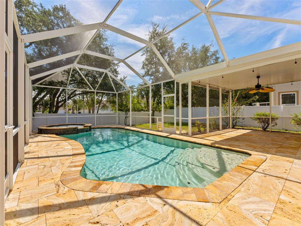 A screened-in pool and hot tub area with stone pavers and a covered patio — 7606 S SPARKMAN STREET, TAMPA, FL