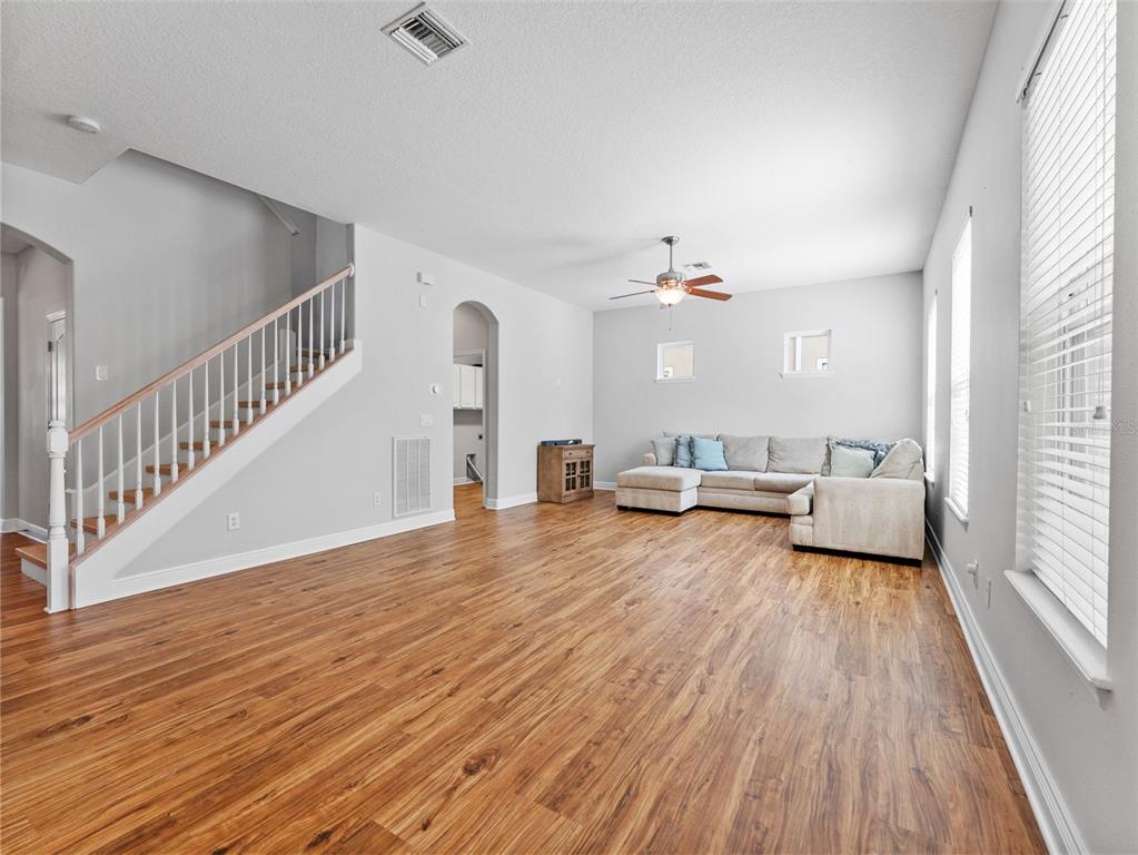 A living room features wood-look flooring, a staircase with white railings, and a sectional sofa — 7606 S SPARKMAN STREET, TAMPA, FL