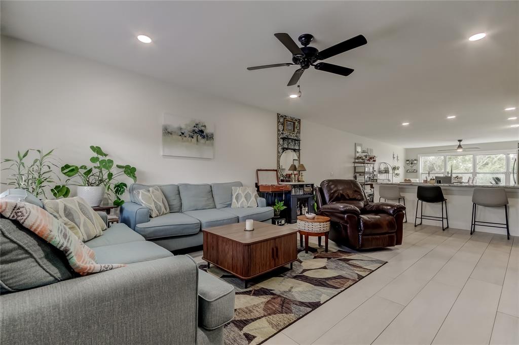 A living room features a blue sofa, a brown leather recliner, and a coffee table — 2170 AMERICUS BOULEVARD N UNIT 64, CLEARWATER, FL