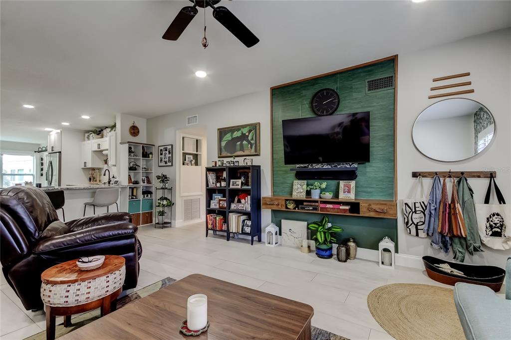 A living room features a blue sectional sofa, a brown leather recliner, and patterned wallpaper — 2170 AMERICUS BOULEVARD N UNIT 64, CLEARWATER, FL