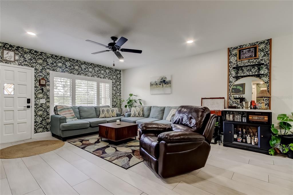 A kitchen features a granite-topped island with three bar stools and white cabinetry — 2170 AMERICUS BOULEVARD N UNIT 64, CLEARWATER, FL