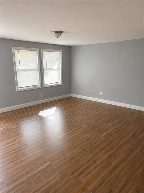 An empty room features light gray walls, wood-look flooring, two windows, and a ceiling light — 407 S ANDERSON STREET, BUNNELL, FL
