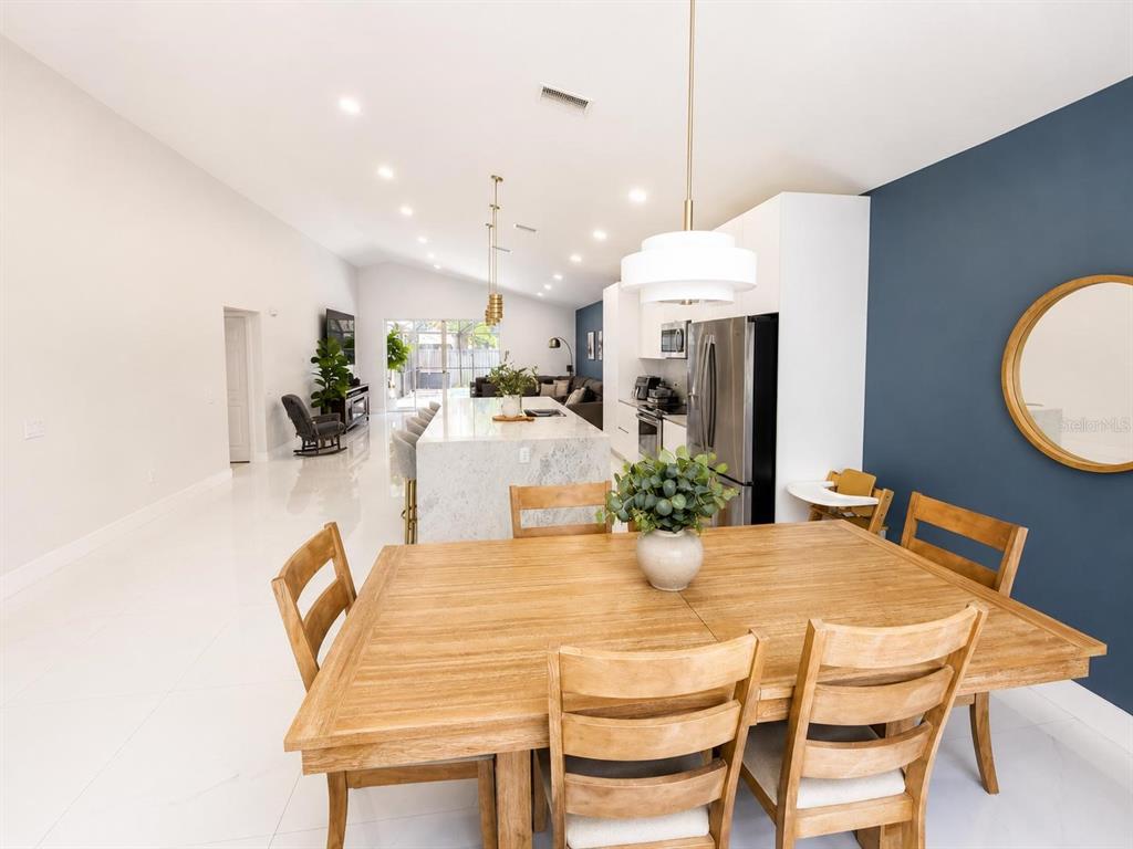 A dining area with a wooden table leads into a modern kitchen with a marble island — 3728 COLD CREEK DRIVE, VALRICO, FL