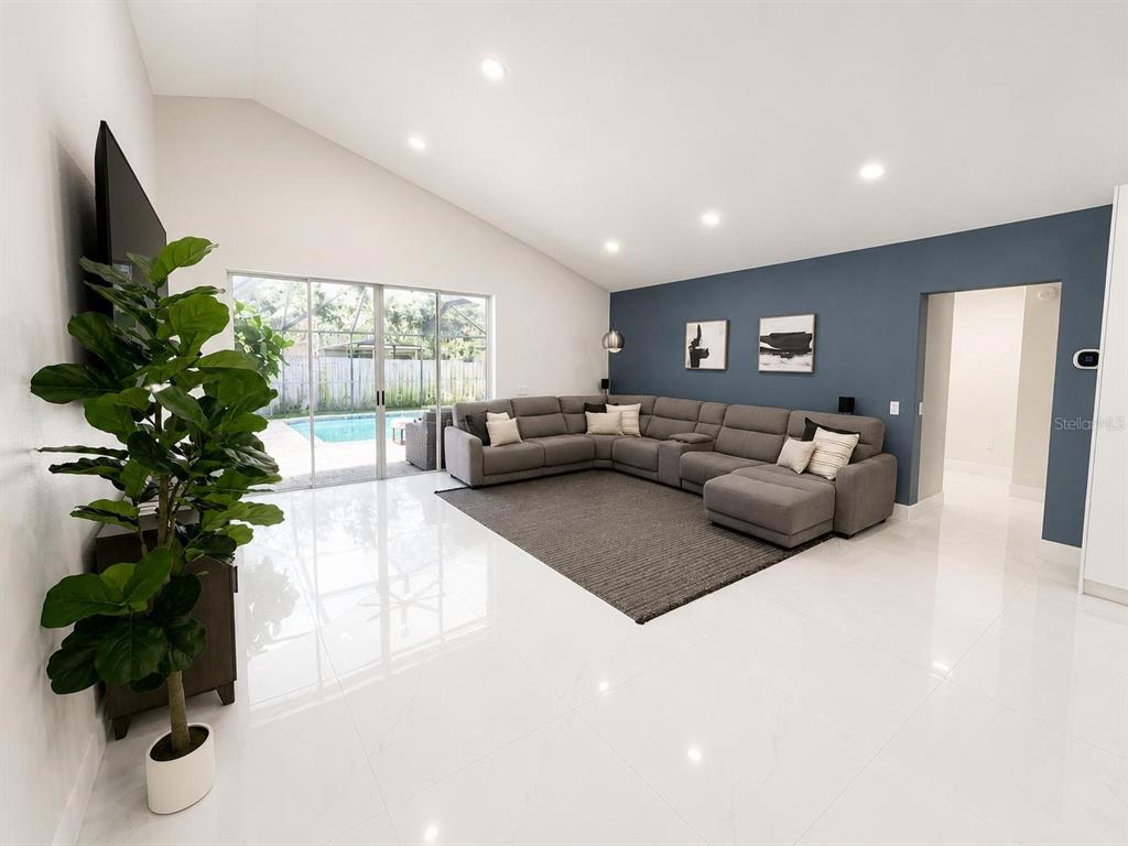 A spacious living room features white tile floors, a blue accent wall, and a sectional sofa — 3728 COLD CREEK DRIVE, VALRICO, FL