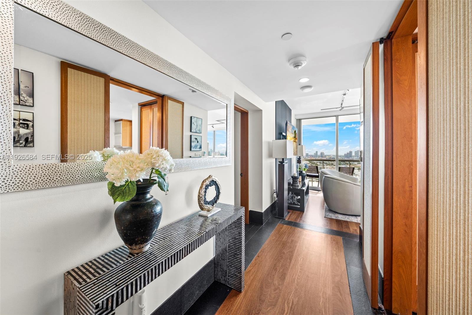 A hallway features a console table, a large mirror, and a view of a living area — 101 20th St # 3202, Miami Beach FL 33139, MIAMI BEACH, FL