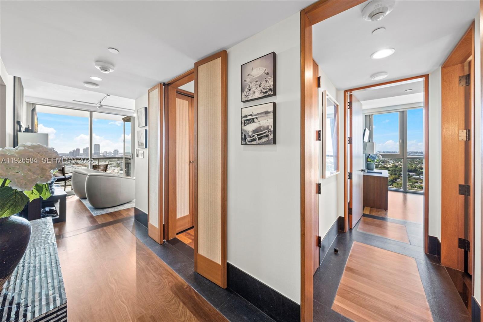A hallway with wood and dark stone flooring leads to two rooms with floor-to-ceiling windows — 101 20th St # 3202, Miami Beach FL 33139, MIAMI BEACH, FL