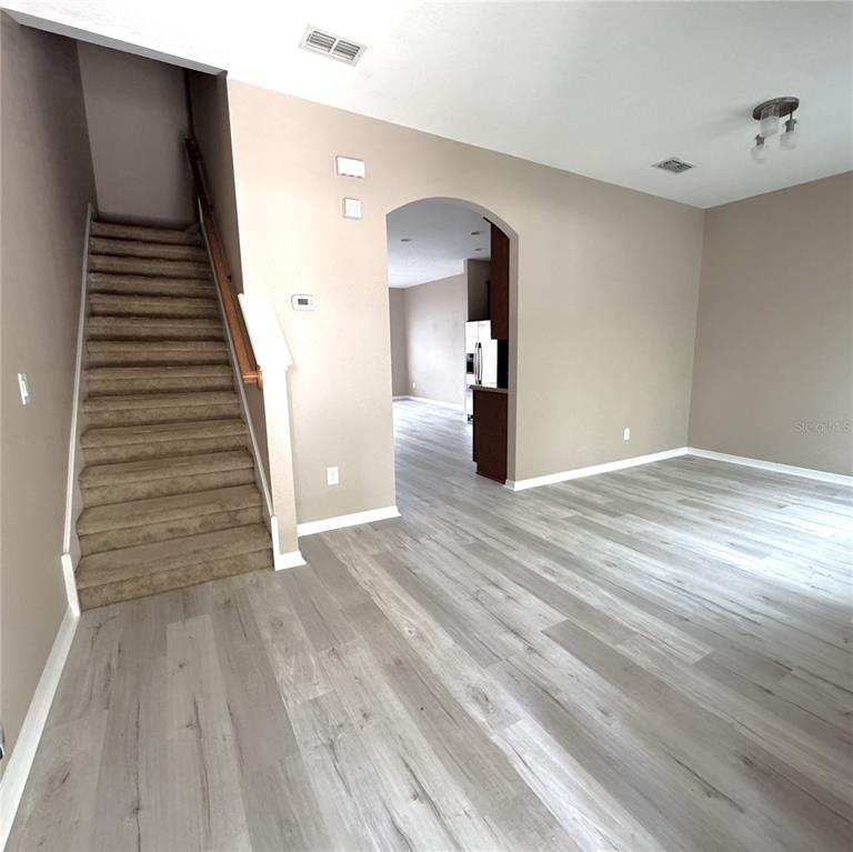 A carpeted staircase leads upstairs next to an arched entryway into a kitchen area — 12937 EMERSONDALE AVENUE, WINDERMERE, FL