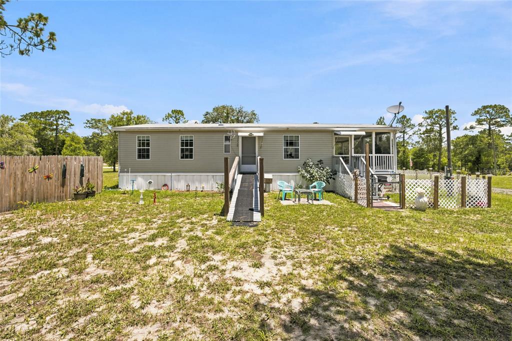 A single-story manufactured home features light siding, a wheelchair ramp, and a screened-in porch — 13330 SE 21ST PLACE, MORRISTON, FL