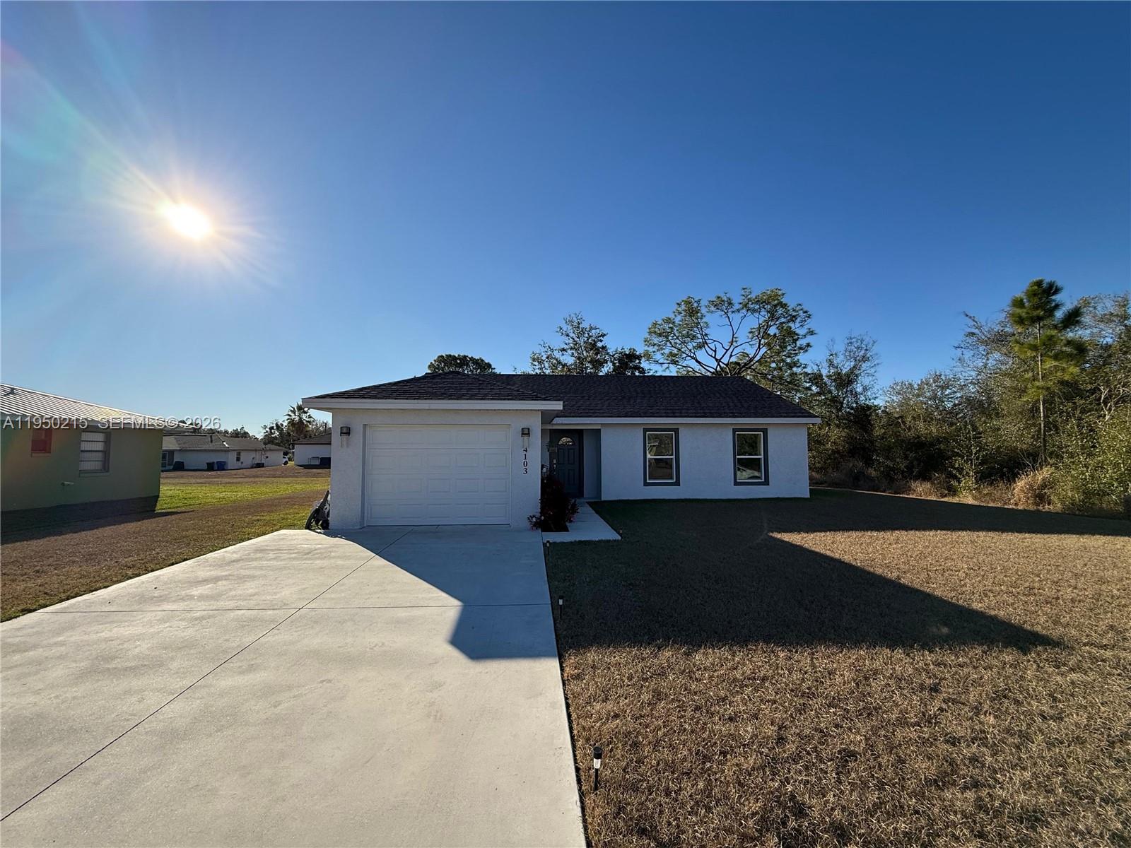 A single-story white house with a garage and a concrete driveway under a clear sky — 4103 Loretto Ave, Sebring FL 33872, SEBRING, FL