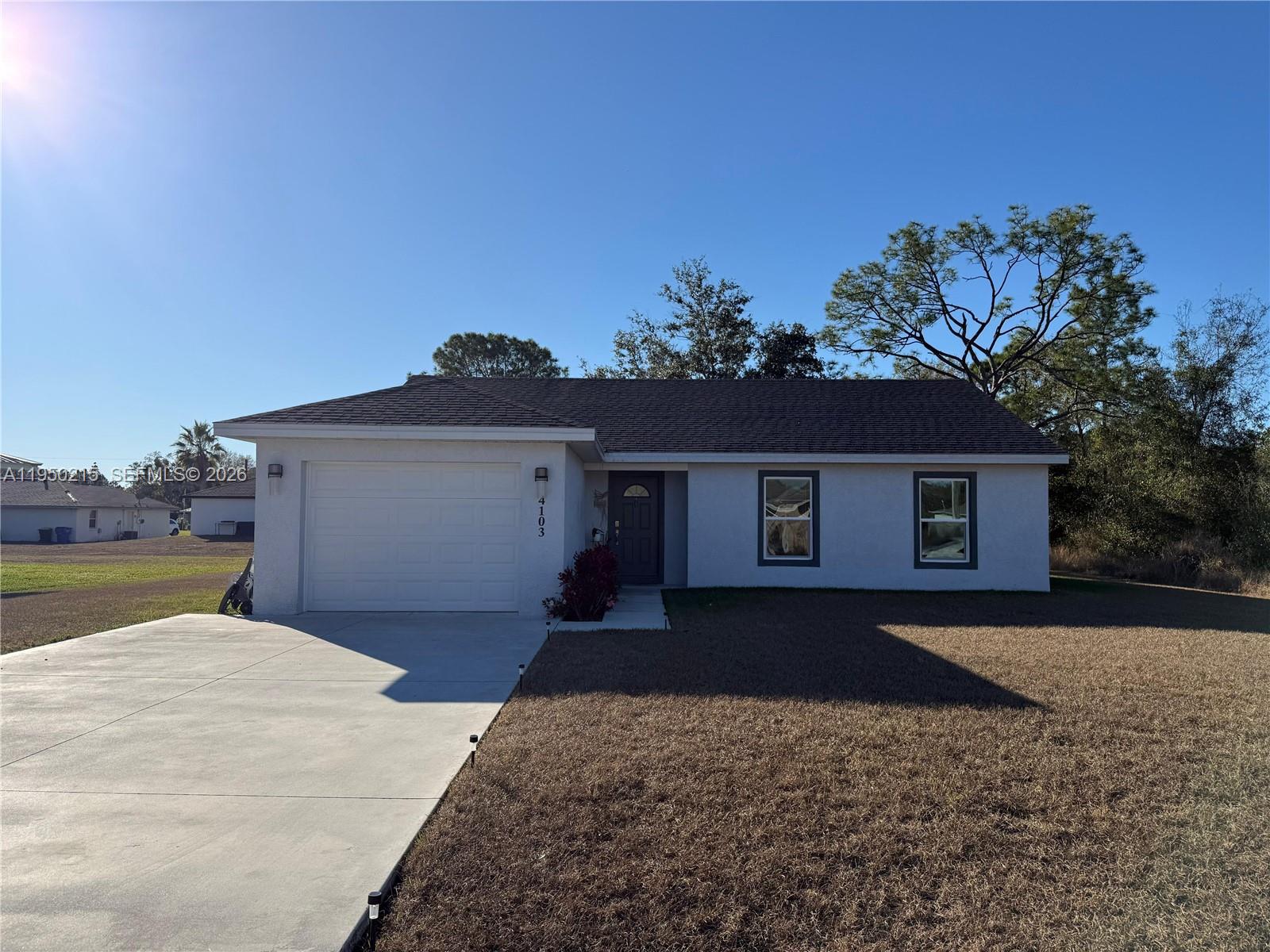 A single-story house with a white stucco exterior, a garage, and a concrete driveway — 4103 Loretto Ave, Sebring FL 33872, SEBRING, FL