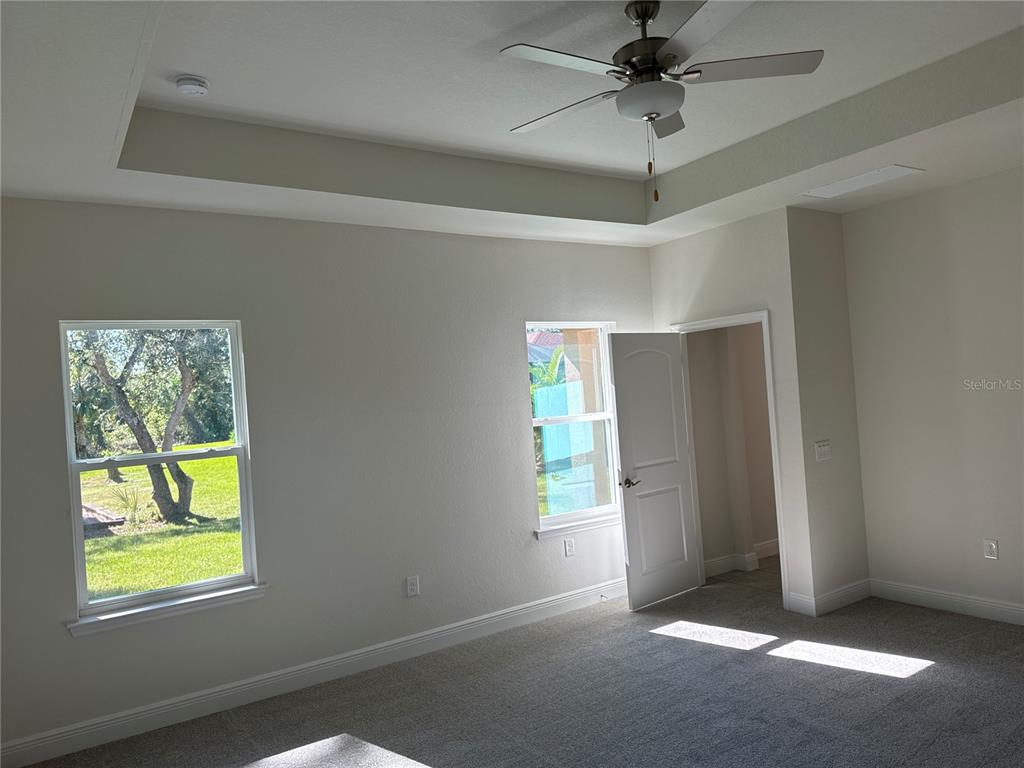 A bedroom with gray carpet, a tray ceiling, a ceiling fan, and two windows — 1409 MARJORIE LANE, NORTH PORT, FL