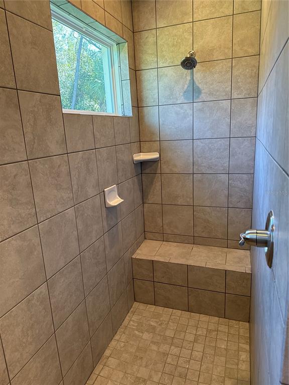 A tiled walk-in shower features a built-in bench, a window, and two soap dishes — 1409 MARJORIE LANE, NORTH PORT, FL